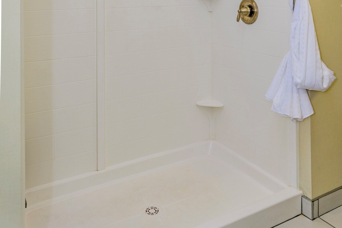 A walk-in shower with a glass door, a towel rack, and a showerhead.
