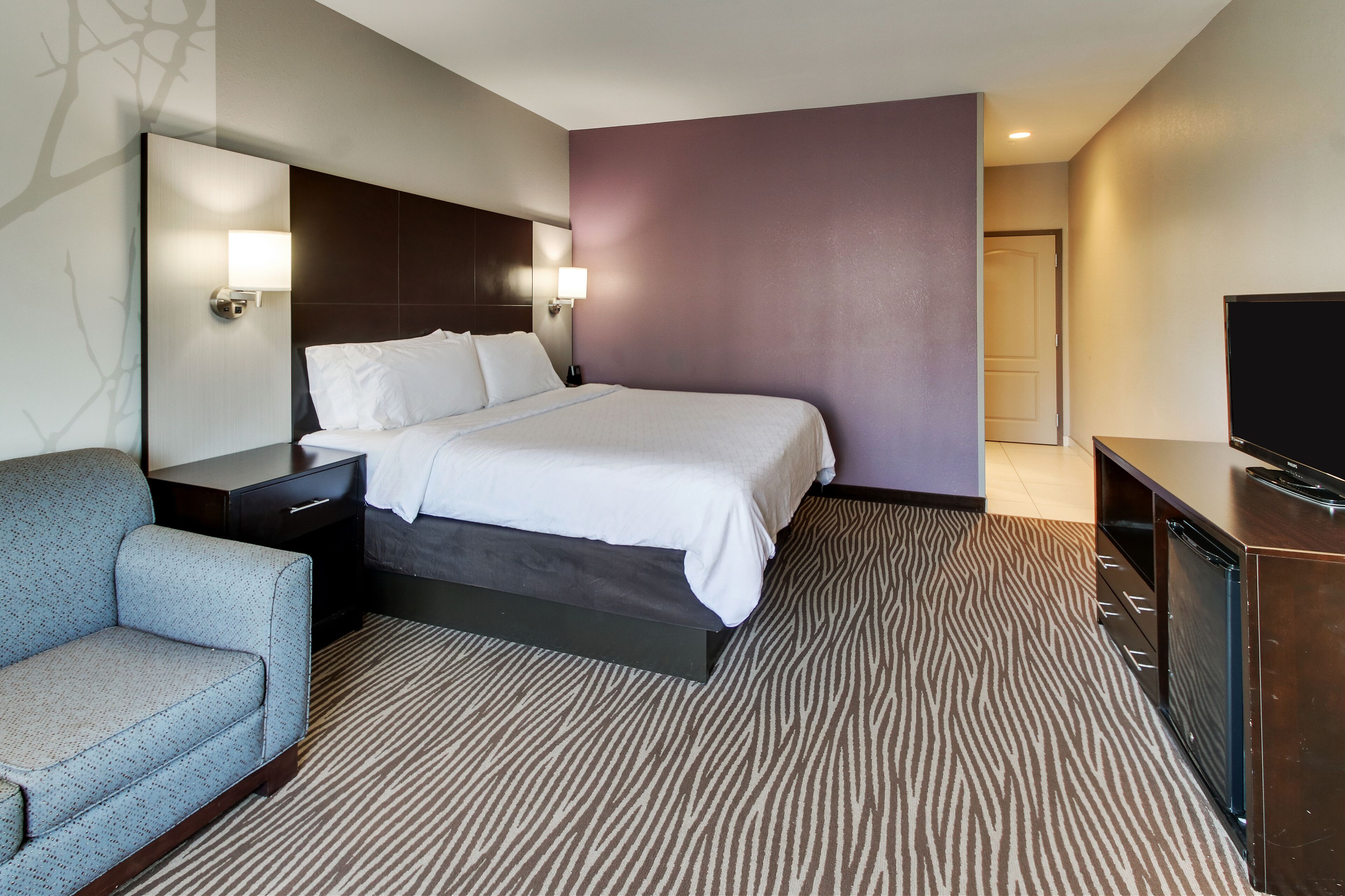 A hotel room with a bed, a sofa, a TV, and a desk.