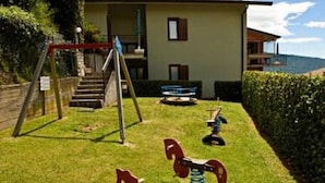 A building with a grassy area in front, a swing set, and a bench.