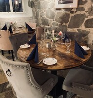 Un tavolo da pranzo apparecchiato con piatti, bicchieri e una candela, circondato da poltrone imbottite.