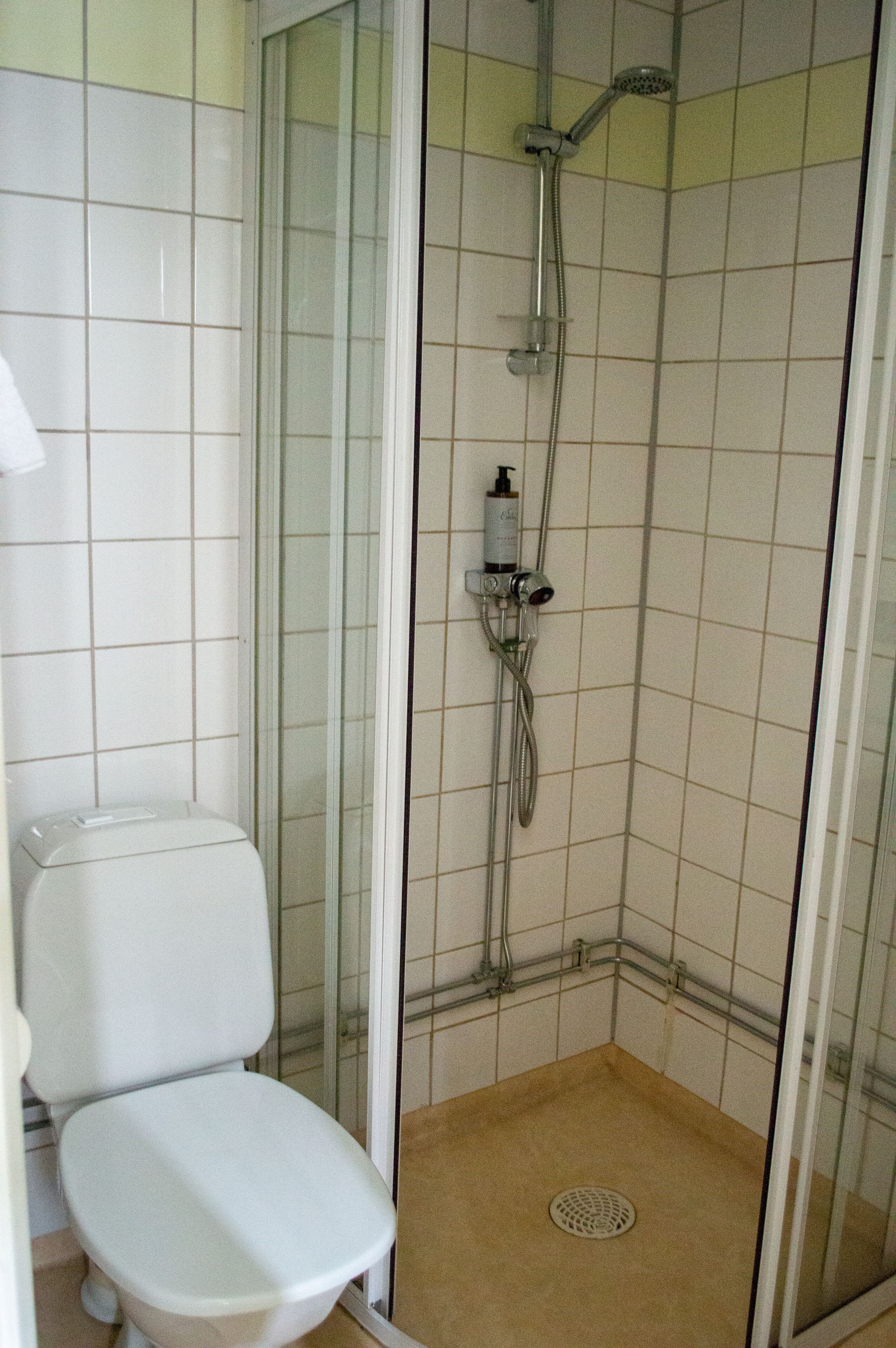 A bathroom with a toilet, a shower enclosure, and a tiled floor.
