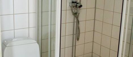 A bathroom with a toilet, a shower enclosure, and a tiled floor.