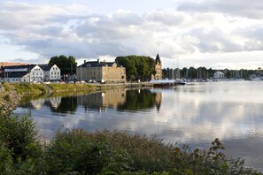 A calm river with boats, a historic building, and a church in the background. - Hotell Blå Blom (Värmdö)