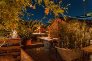 An outdoor patio area with a table and chairs, potted plants, and a lantern. - Casa D'aria (Catania)