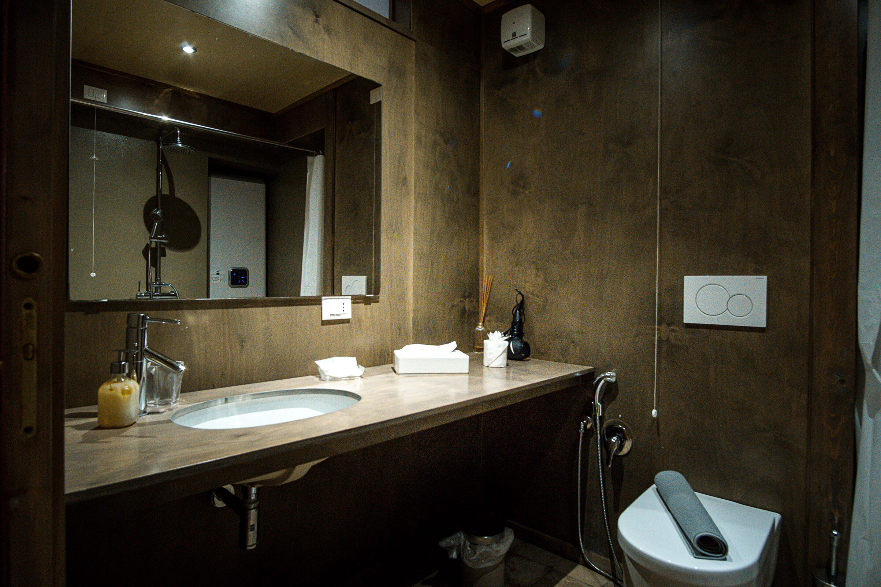 Ein modernes Badezimmer mit einem großen Spiegel, einem Waschbecken, einer Toilette und einer Dusche.