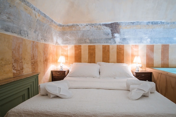 A hotel room with a bed, two bedside tables with lamps, a wooden headboard, and a view of a swimming pool.