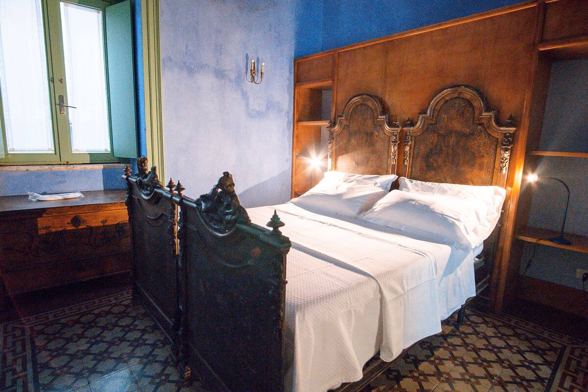 Une chambre à coucher avec une tête de lit en bois, un lit recouvert de draps blancs, une table de chevet et une fenêtre donnant sur un beau paysage.