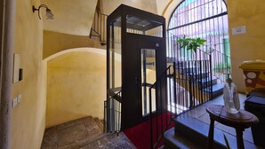 Una escalera con alfombra roja que conduce a un balcón con barandilla de metal.