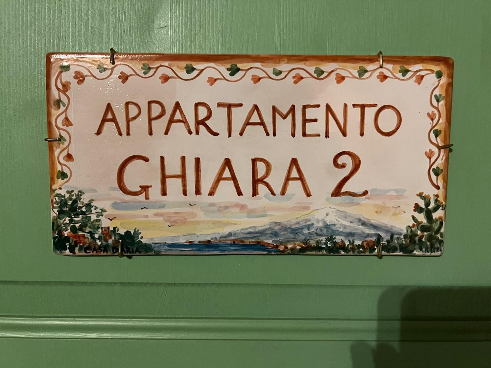 Schild für 'APARTAMENTO GHIARA 2' mit Illustration einer Berglandschaft.