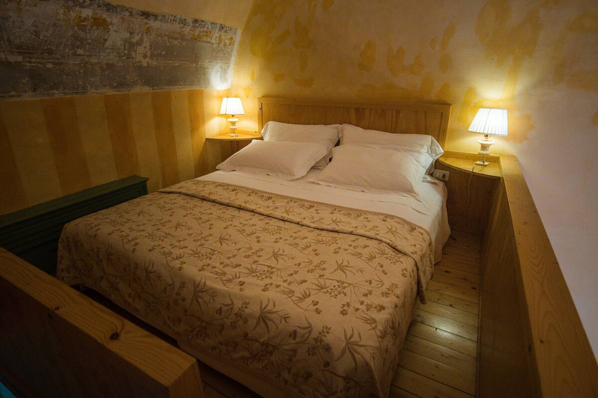 Une chambre à coucher avec un lit en bois, deux tables de chevet avec des lampes et un banc en bois.