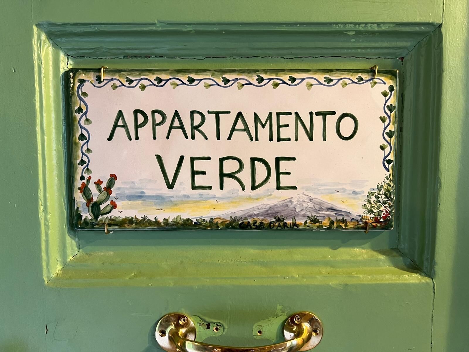 A door with a sign that reads "APARTAMENTO VERDE" and a mountain landscape.
