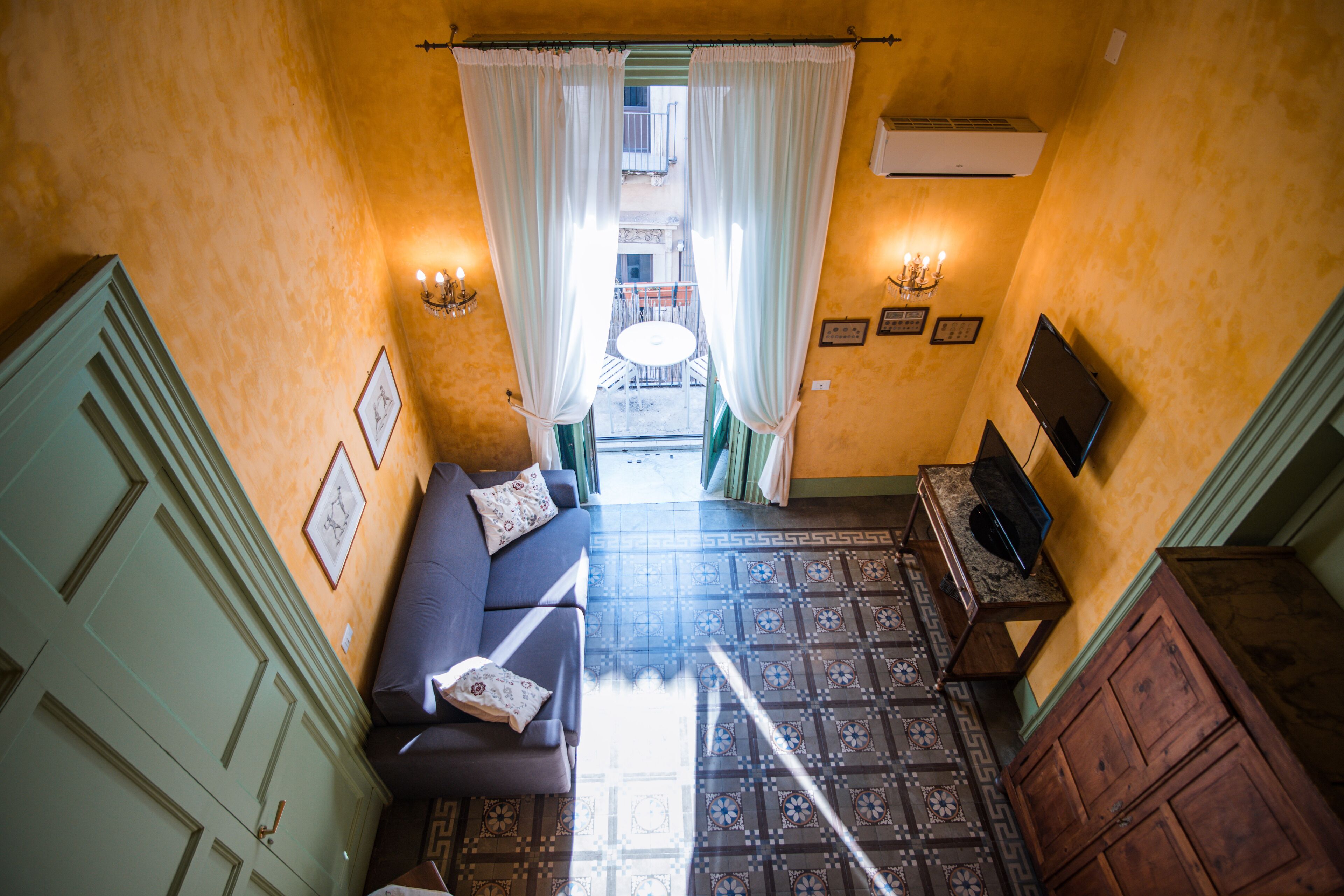 A narrow hallway with a sofa, a television, and a patterned floor.
