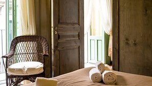 Una habitación con una cama, una silla de mimbre y una puerta.