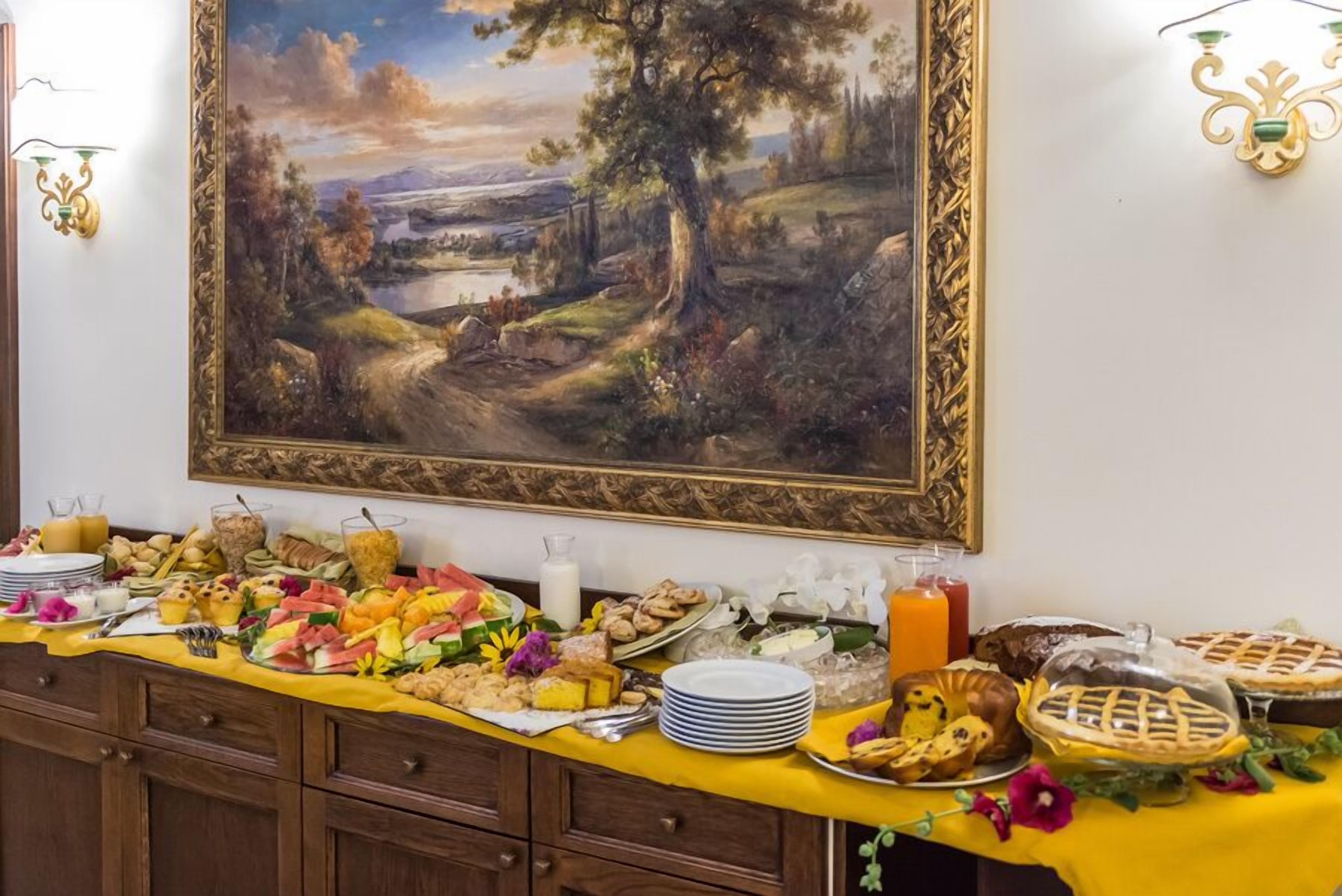Ein reichhaltiges Buffet mit verschiedenen Speisen und ein großes Landschaftsbild an der Wand.