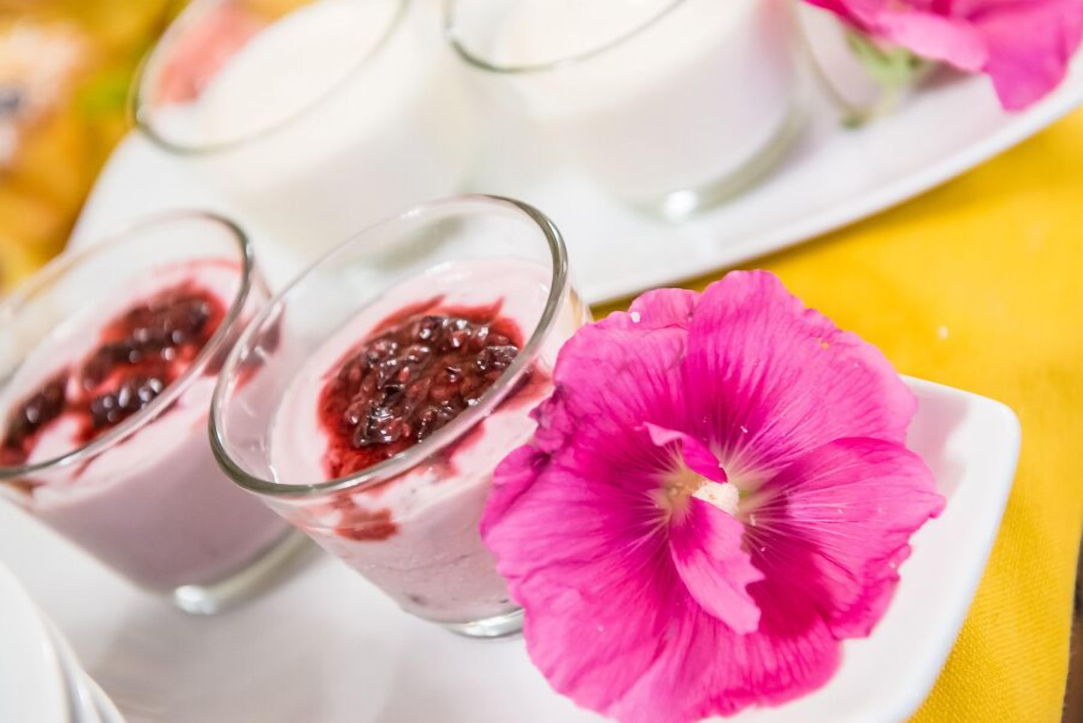 Una fuente de copas de postre con una flor rosa al lado.