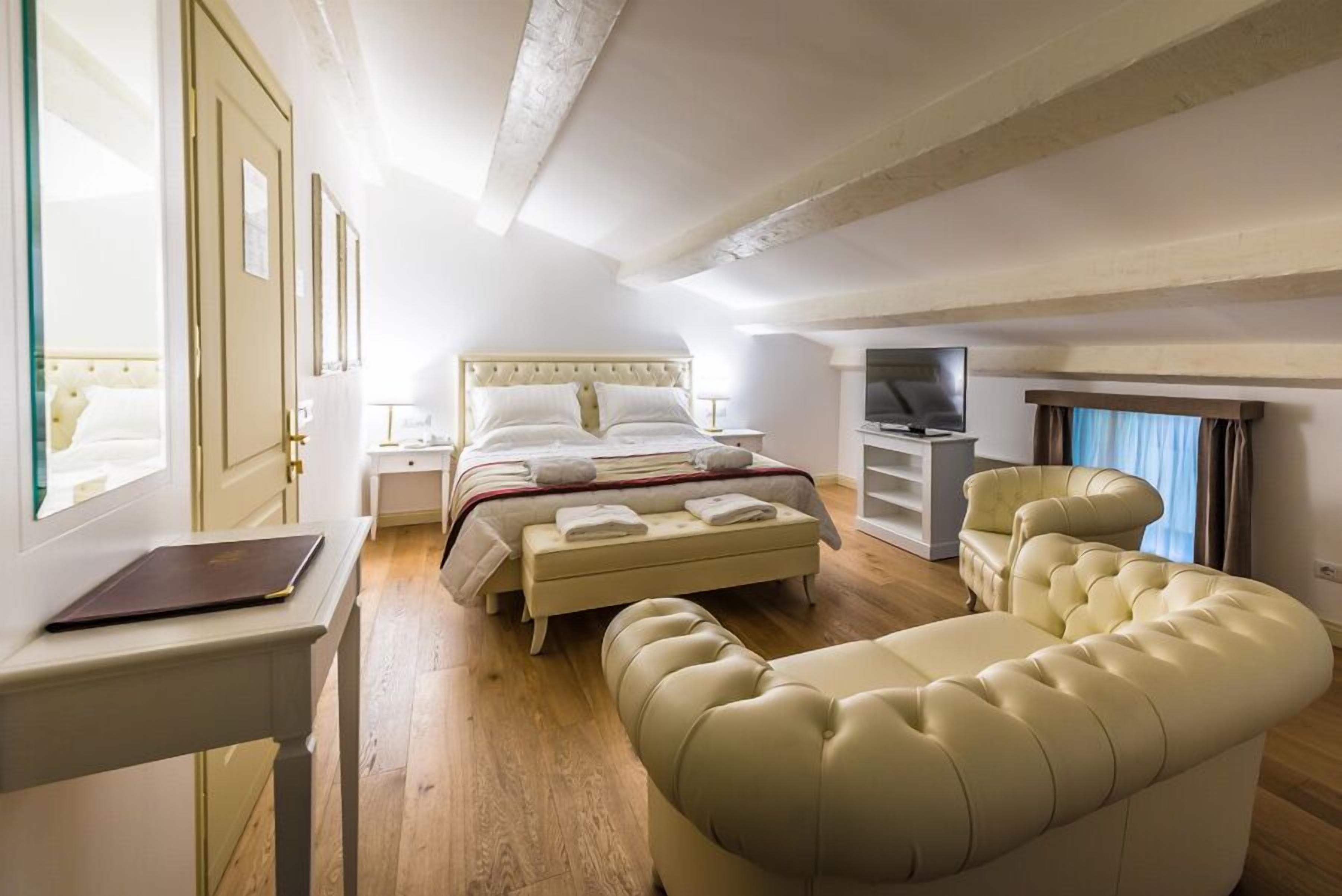 A bedroom with a bed, a desk, a chair, and a television.
