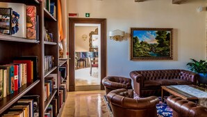 A cozy living room with a leather sofa, a bookshelf filled with books, and a painting on the wall. - Relais Paradiso (Gualdo Cattaneo)