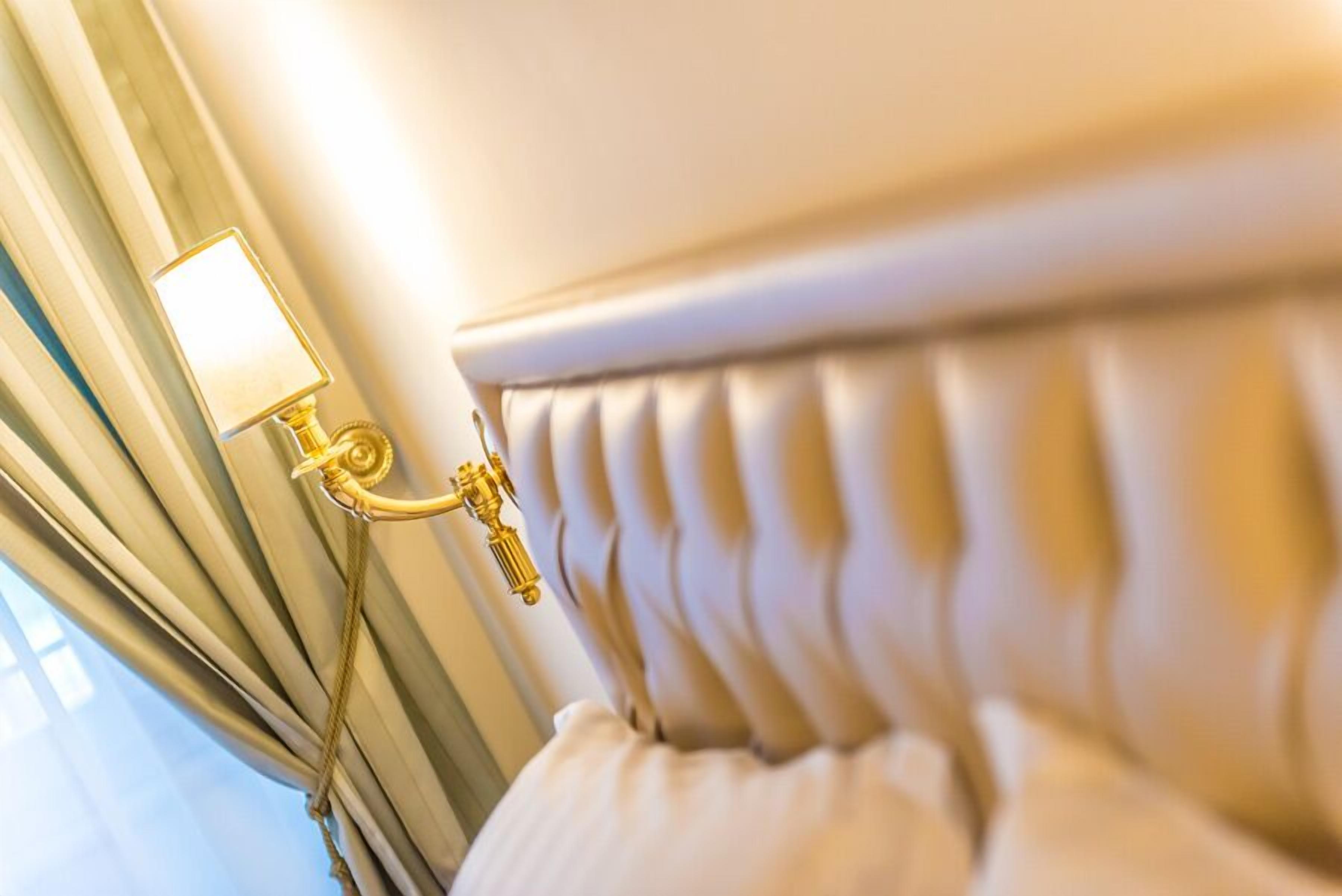 Un gros plan d’une tête de lit dans une pièce, avec un luminaire fixé au mur.