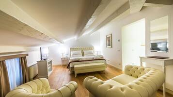 A bedroom with a bed, bedside tables, a TV, and a sofa.