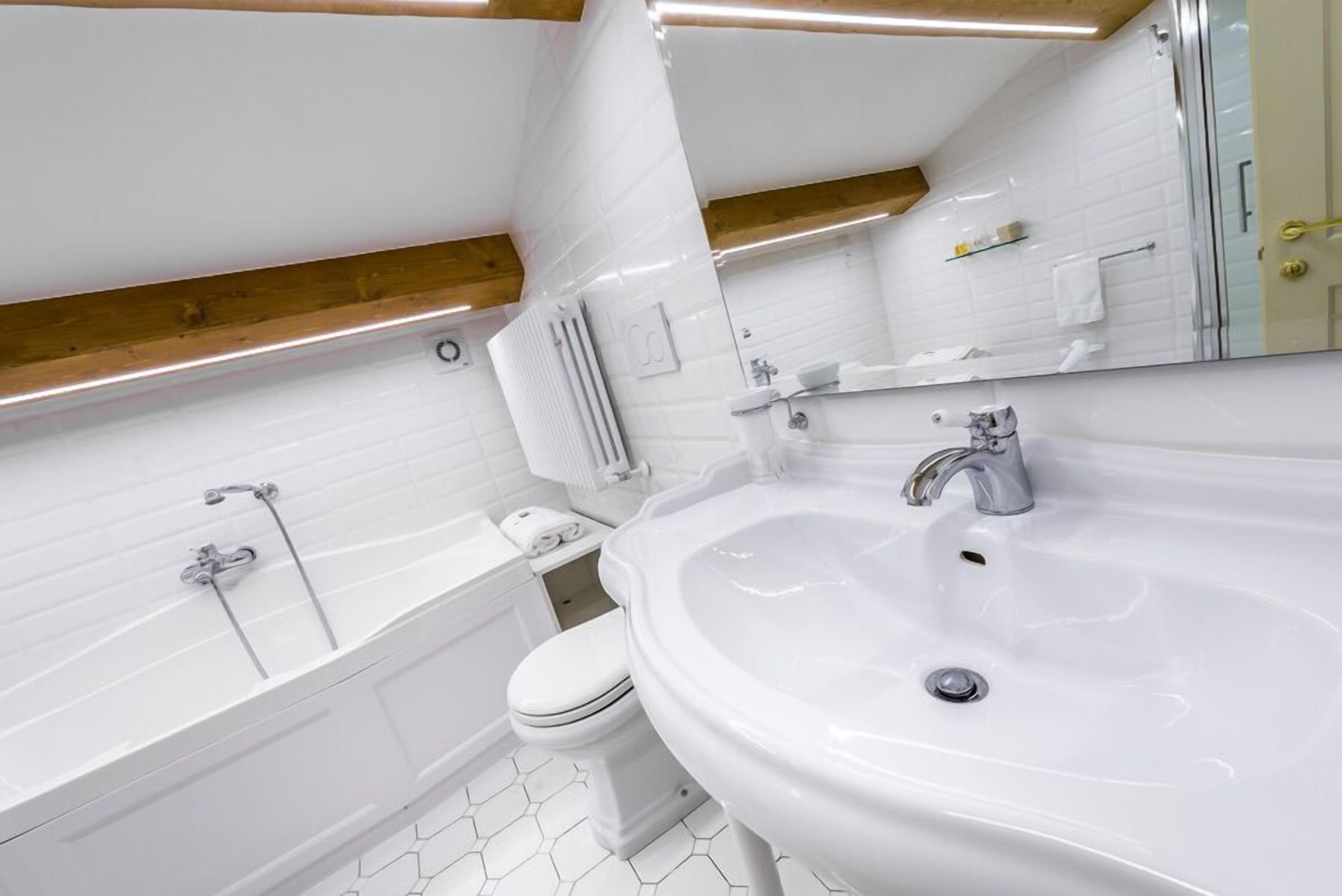 A modern bathroom with a white sink, a bathtub, and a toilet.