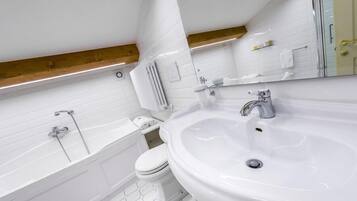 A modern bathroom with a white sink, a bathtub, and a toilet.