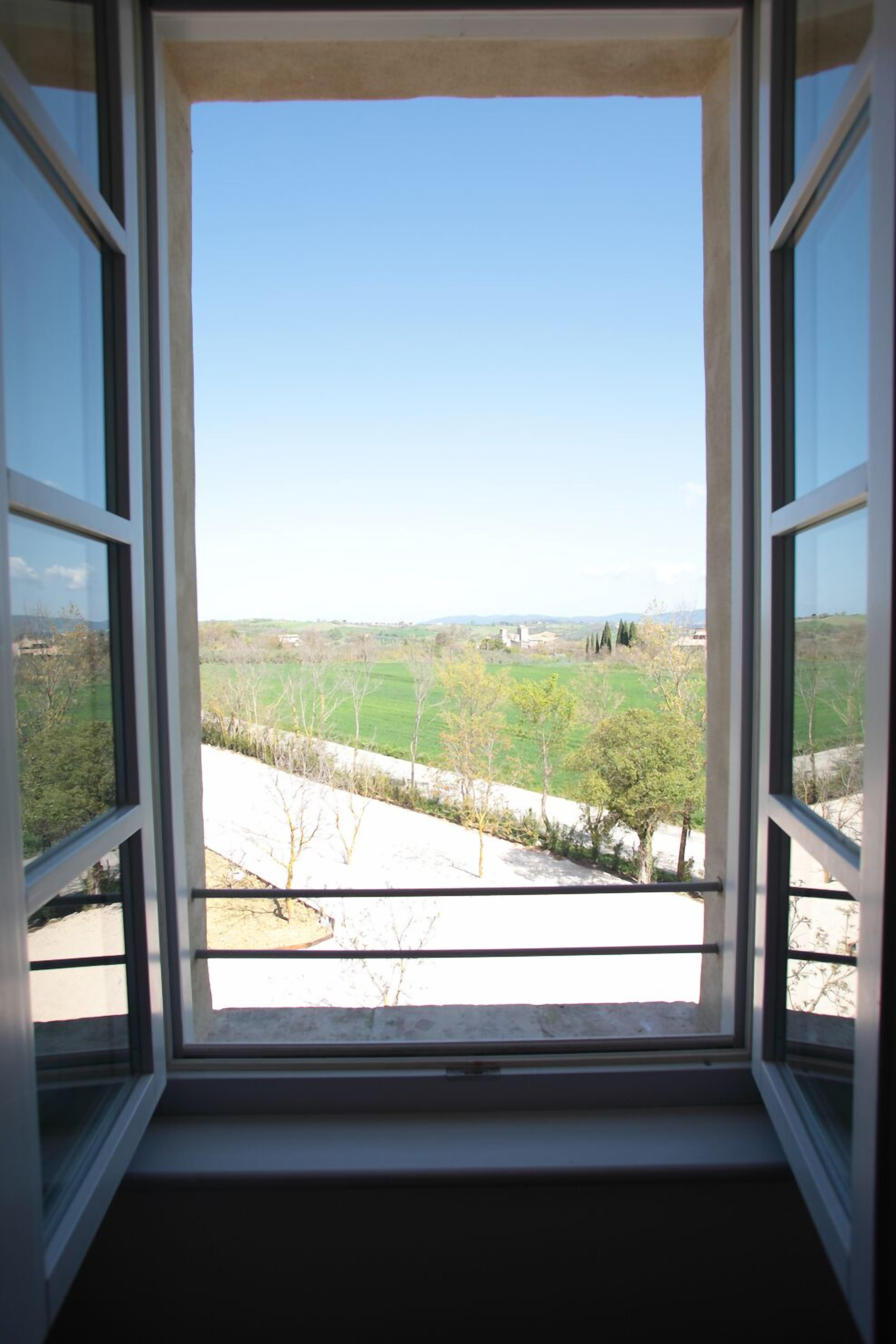 Una ventana con vista a un paisaje verde y colinas lejanas.