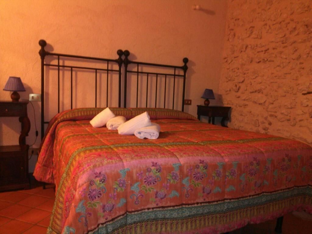 A bed with a floral bedspread, a metal headboard, and two towels.