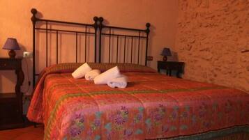 A bed with a floral bedspread, a metal headboard, and two towels.