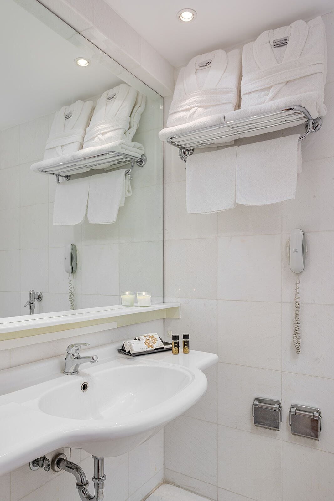 A bathroom with a white sink, mirror, and two towel racks with folded towels.