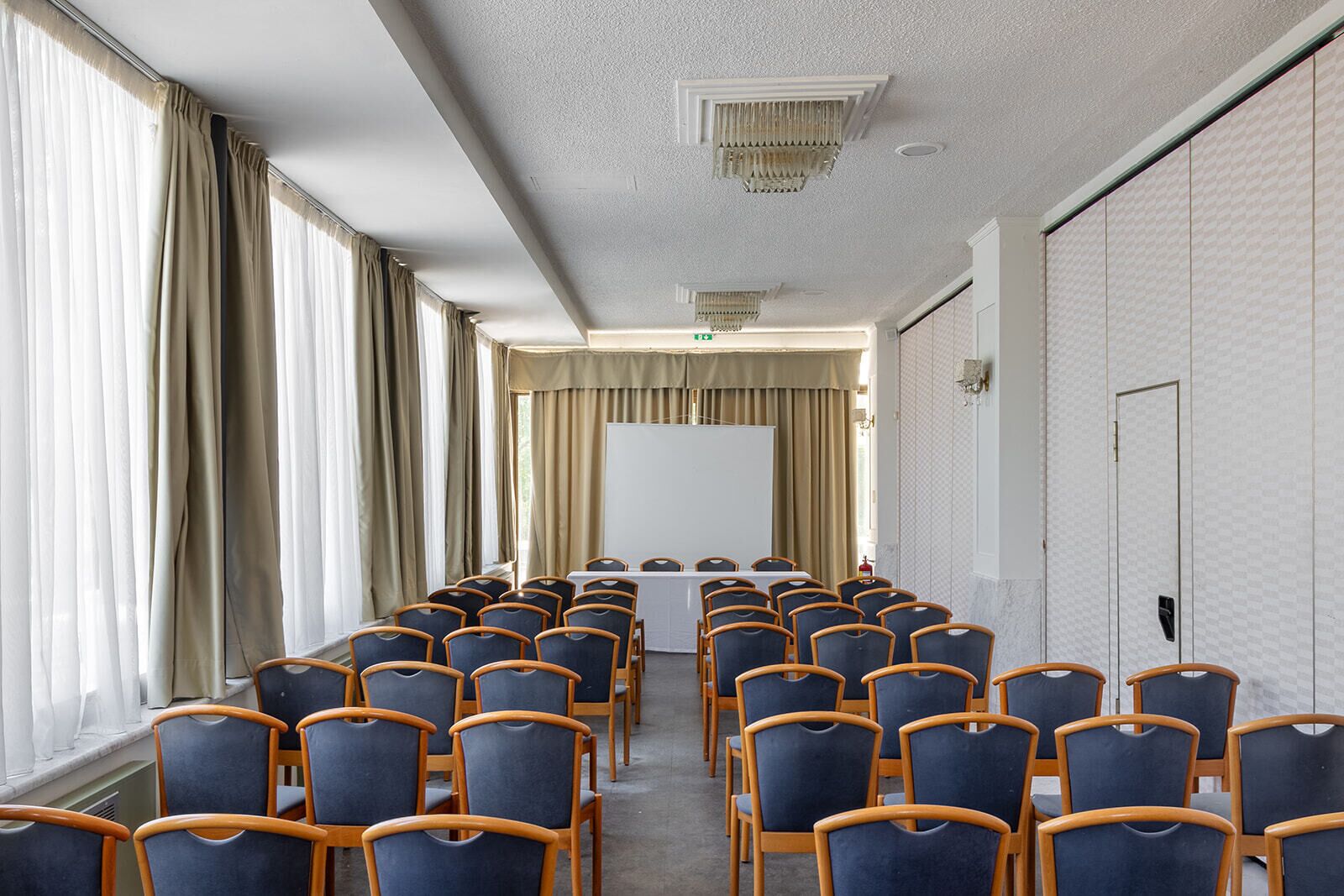 A conference room with rows of chairs, a whiteboard, and a long table.