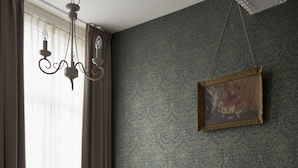 Una cama bien hecha con una colcha color beige, cabecero oscuro y un cuadro colgado en la pared.