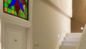 Una escalera con peldaños blancos y barandilla de vidrio, que conduce a un piso de madera.