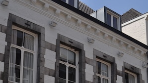 Un edificio histórico con una puerta negra, varias ventanas y un letrero que indica que es un hotel.