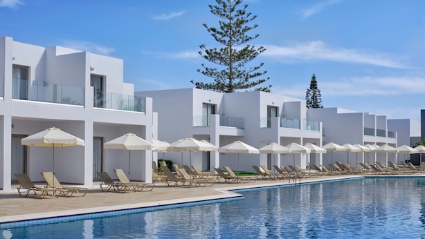 Un hôtel moderne doté d’une piscine, de chaises longues et de parasols.
