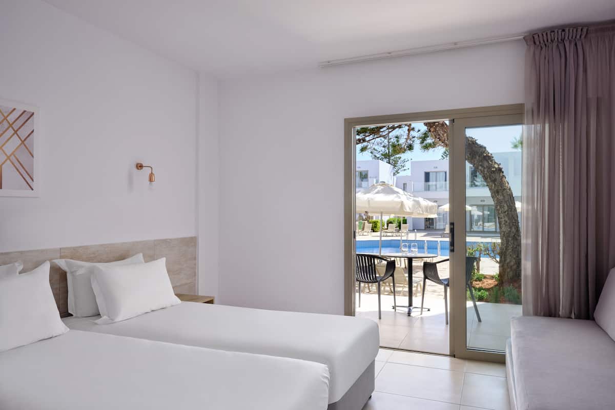 A hotel room with two beds, a balcony with a pool, and a view of the pool area.