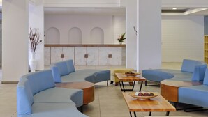 Un hall d'entrée moderne avec des sièges bleus, un comptoir d'accueil et des panneaux décoratifs en bois.