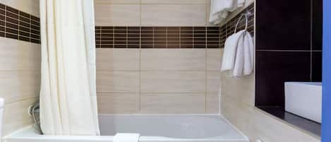 A bathroom with a bathtub, a shower curtain, and a tiled wall with a black accent strip.