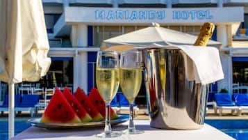A table with two champagne flutes, a bucket of champagne, and a plate of watermelon slices.