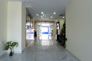 A clean, well-lit reception area with a sign indicating the reception desk, a potted plant, and a Christmas tree.