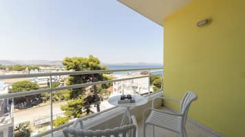 A balcony with a yellow wall, white railing, and two white chairs.