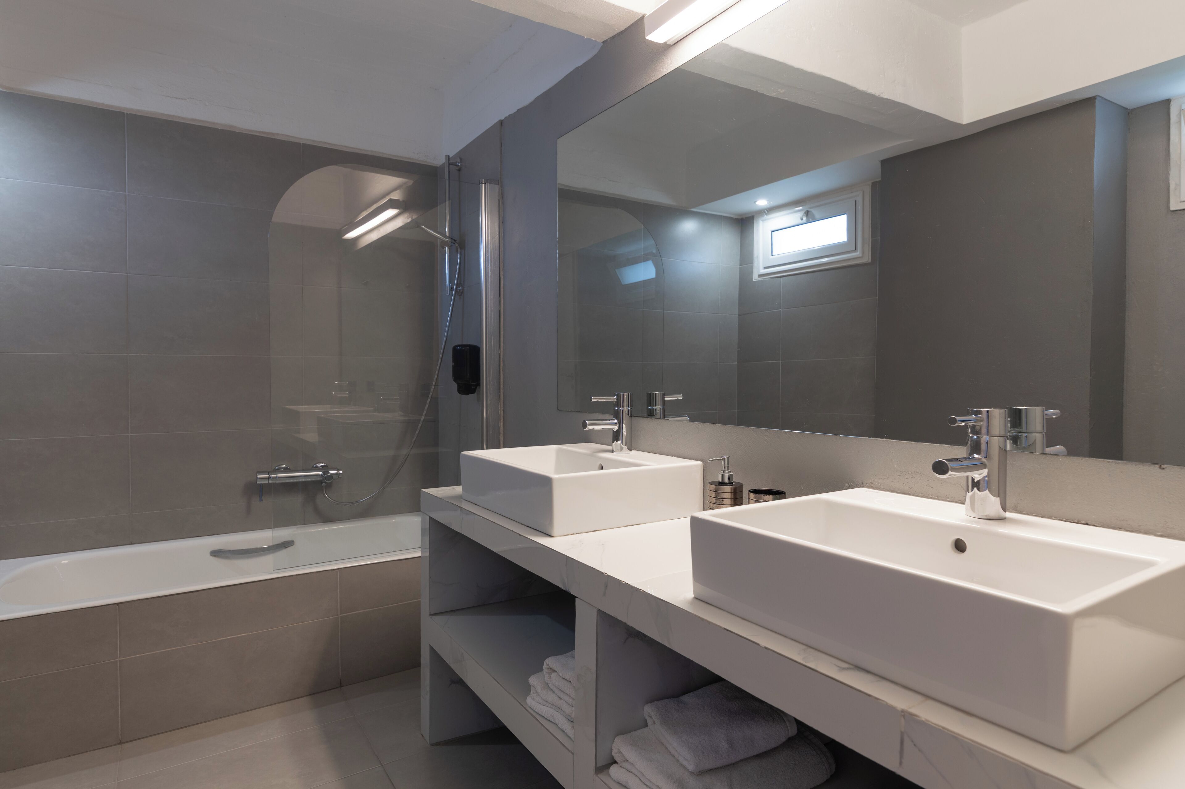 Un baño moderno con dos lavamanos, una bañera y una ducha a ras de suelo.