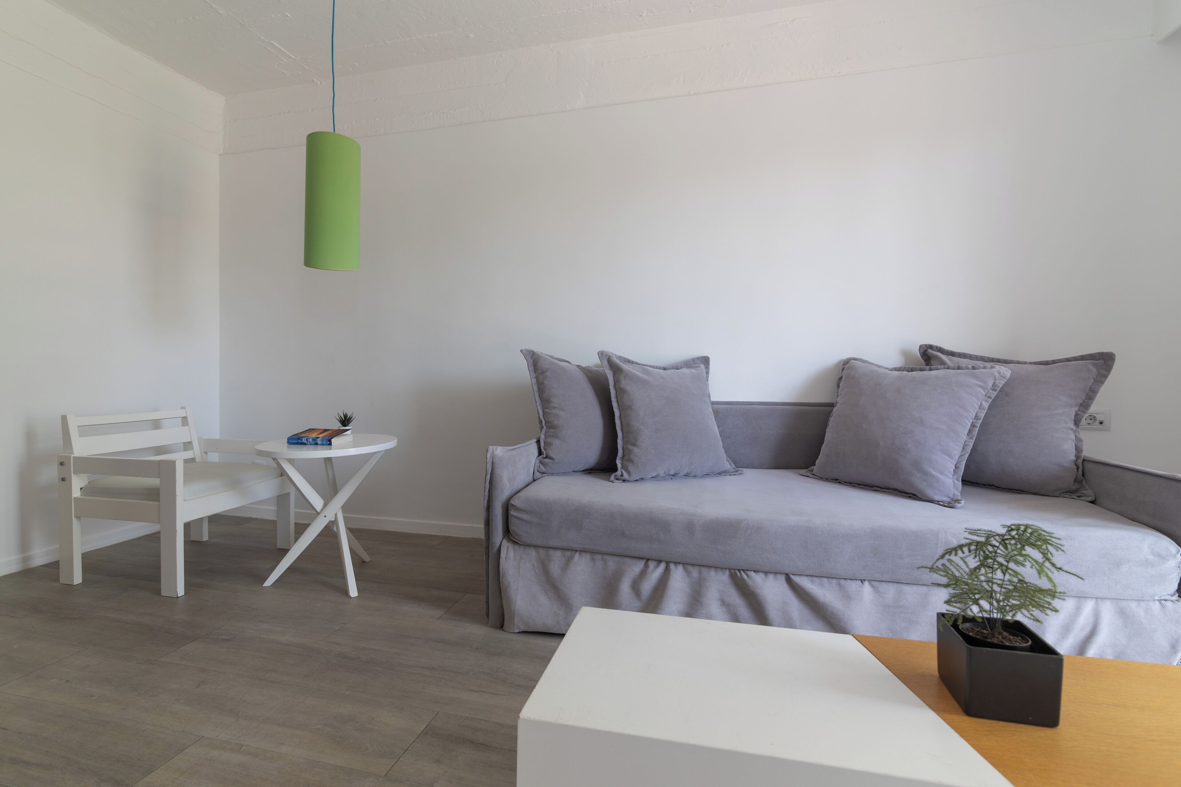 A modern living room with a grey sofa, white armchair, and a small round table.