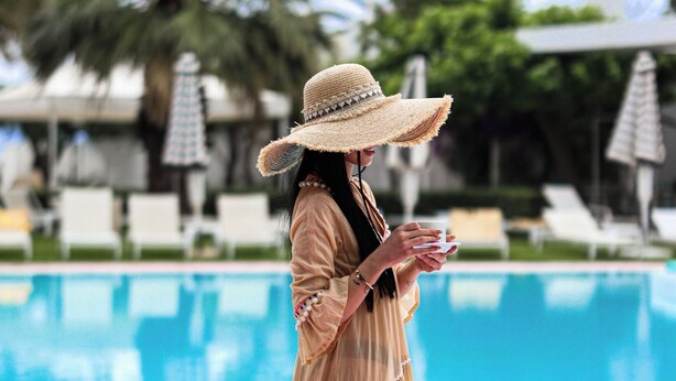 A person standing by a pool with lounge chairs and umbrellas in the background. - Marathon Beach Resort (Marathon)
