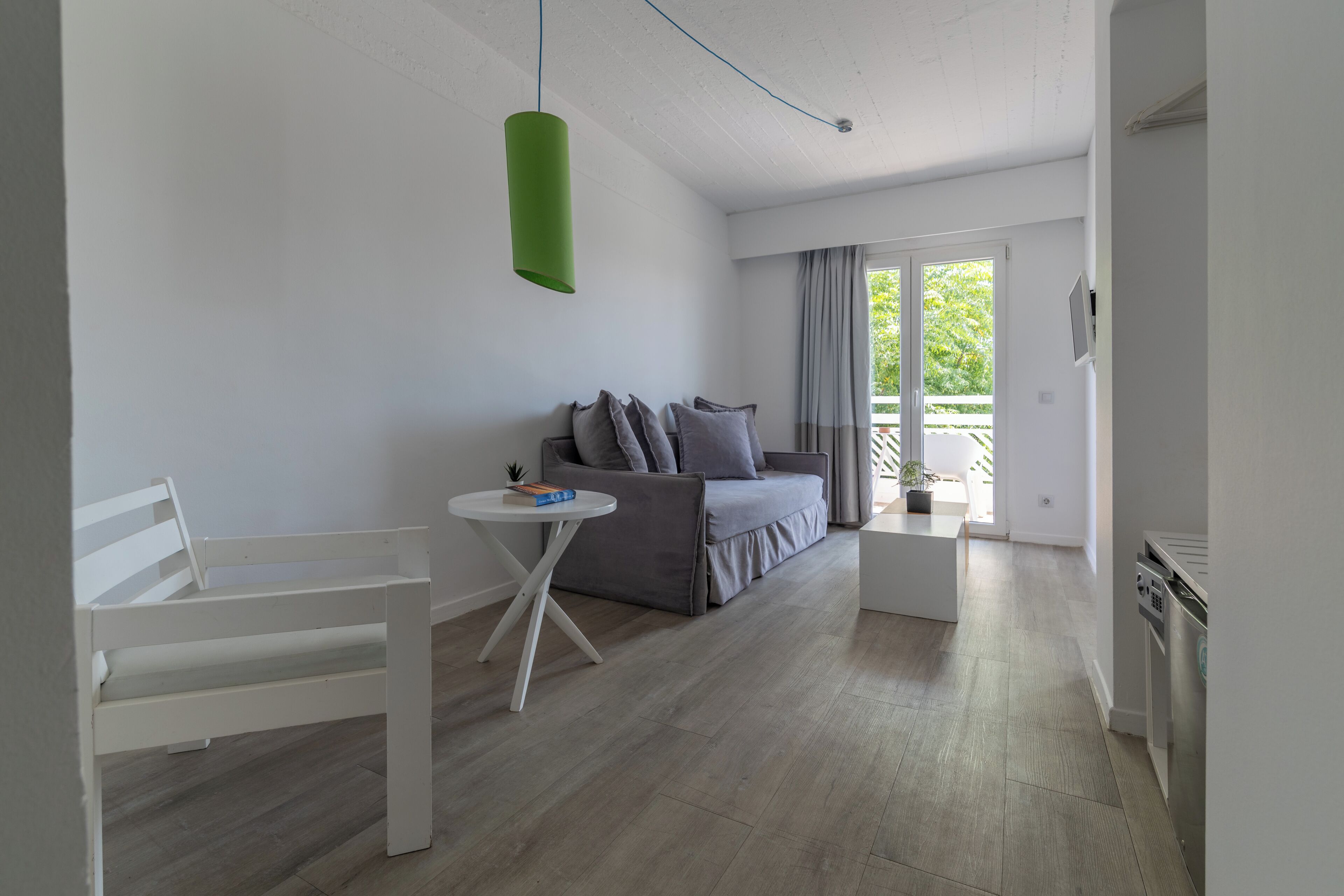 A modern living room with a white sofa, a white chair, and a small round table.