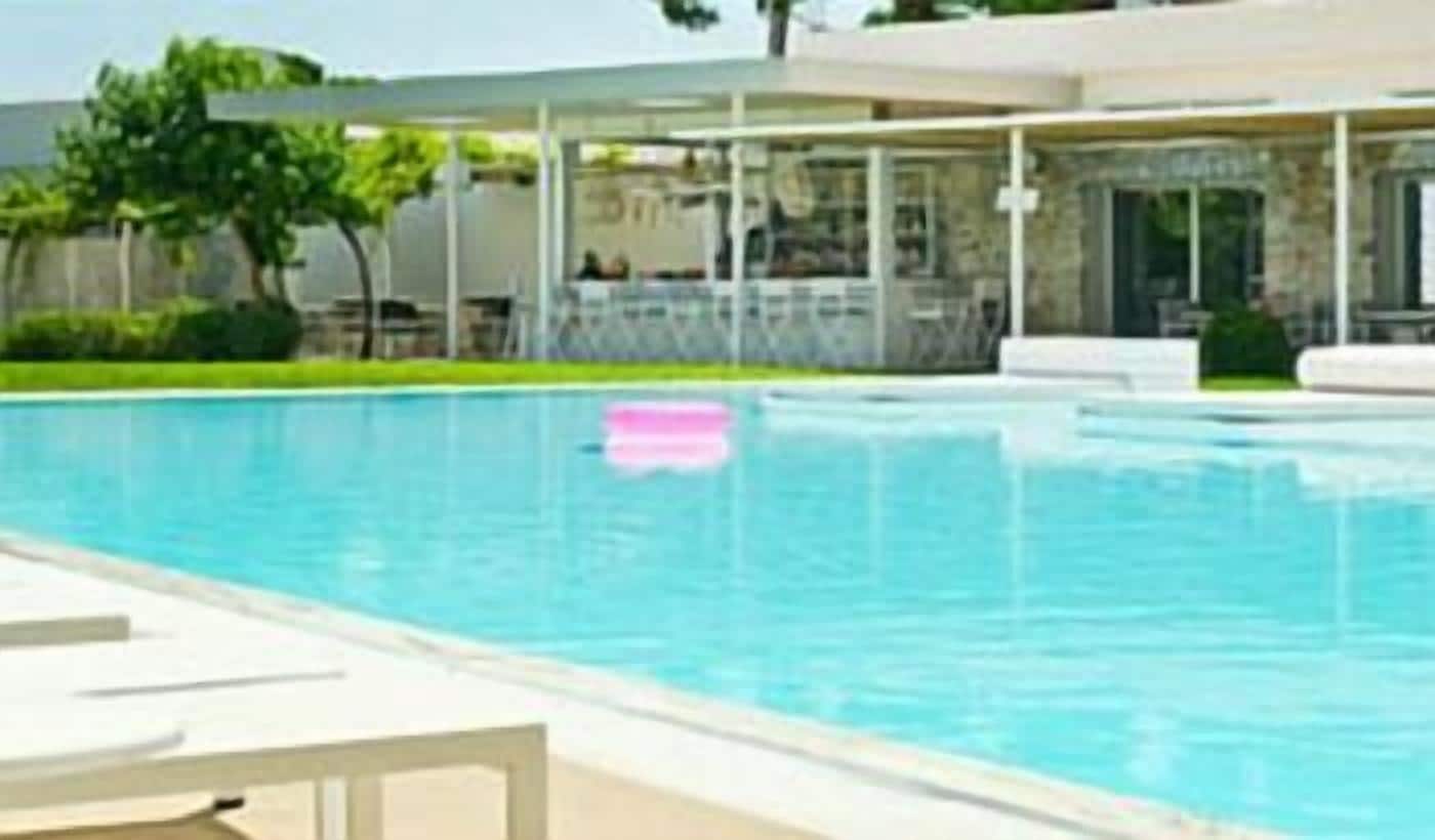 A swimming pool with lounge chairs and a covered area.