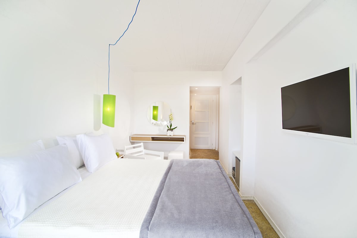 A modern hotel room with a bed, a desk, and a TV.
