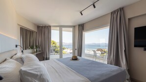 A modern hotel room with a large bed, a TV, and a balcony with a view of the sea. - Marathon Beach Resort (Marathon)