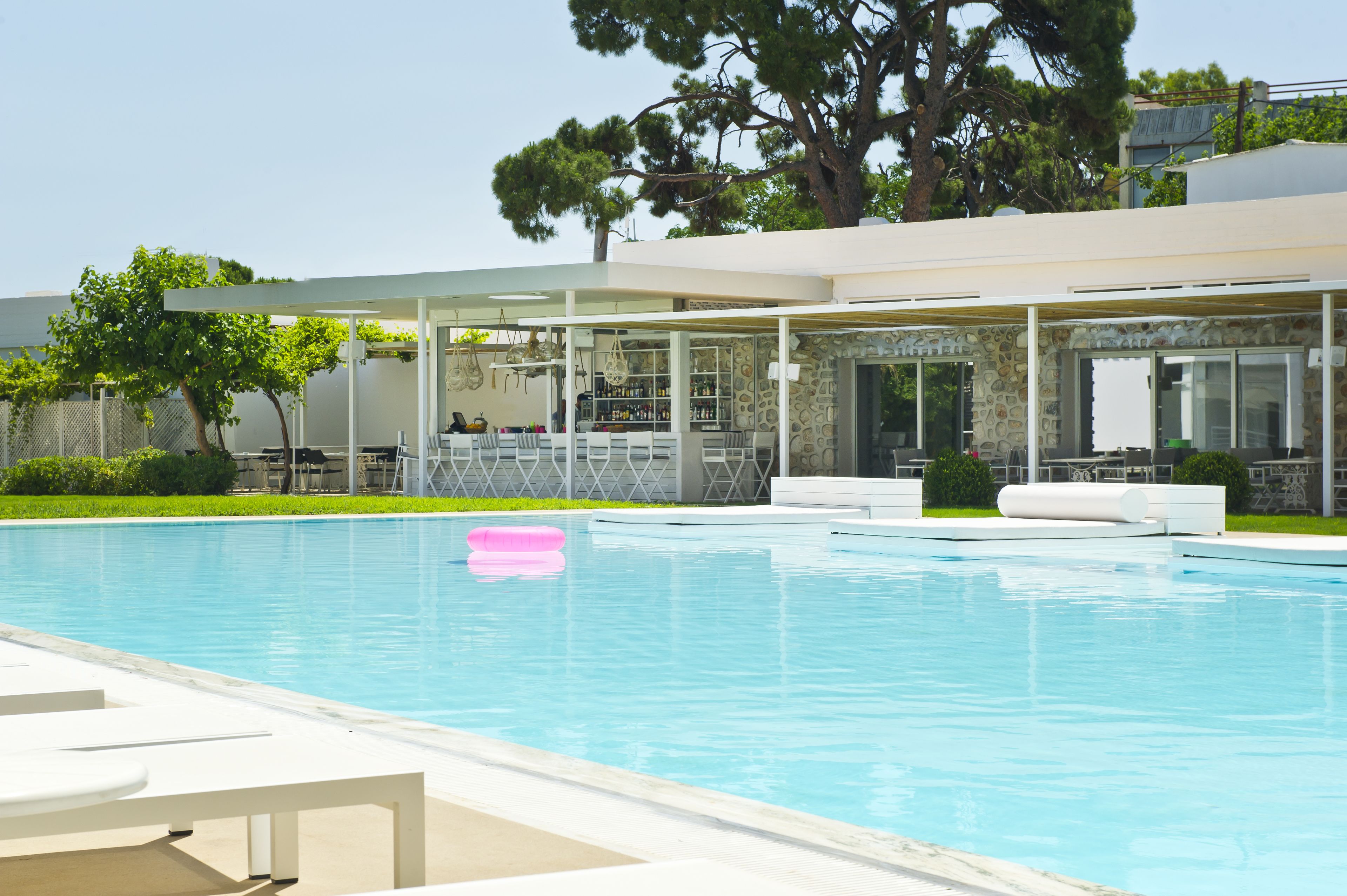 A pool area with lounge chairs, a bar, and a stone facade building.