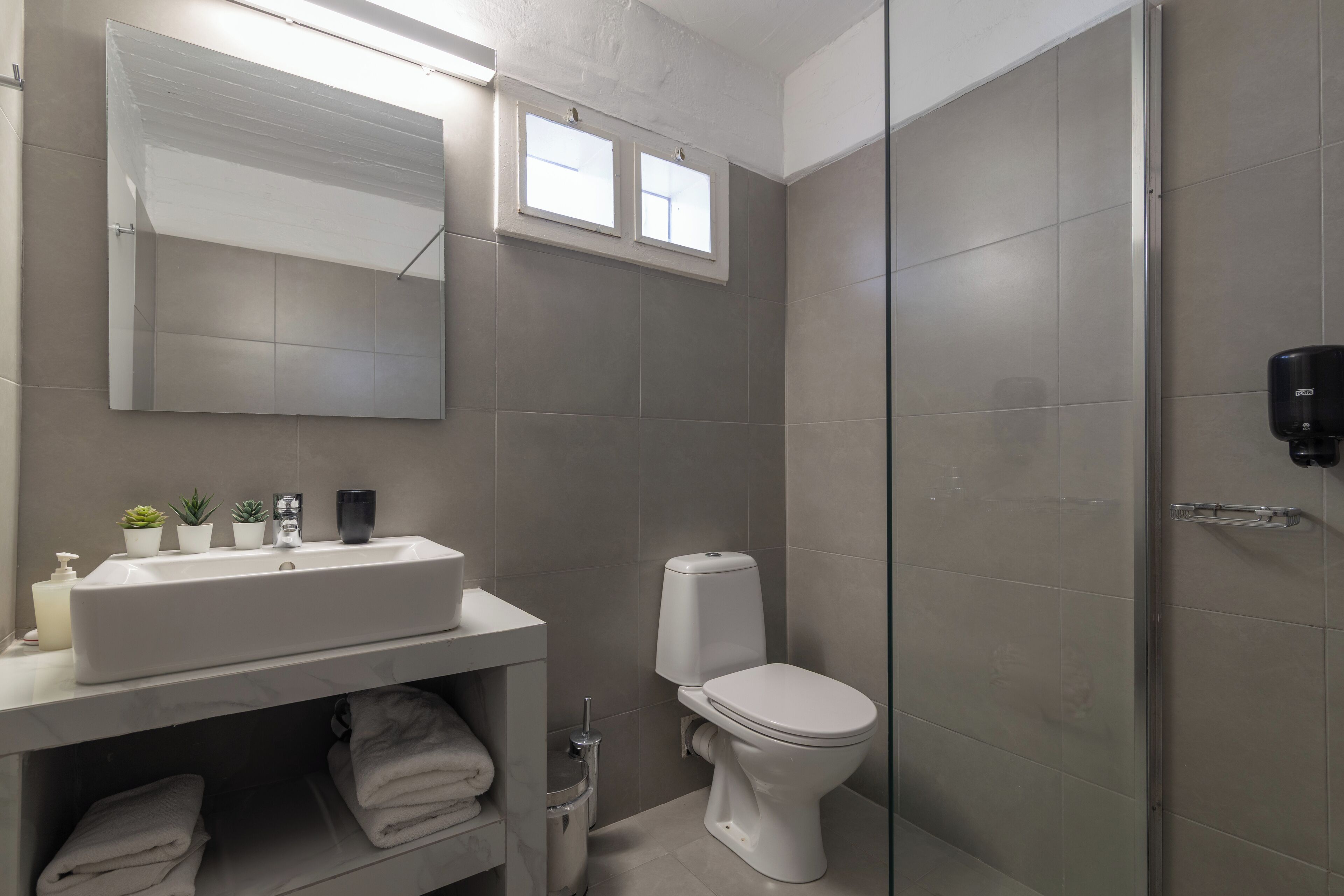Ein modernes Badezimmer mit einem großen Waschbecken, Toilette und einer Duschkabine aus Glas.