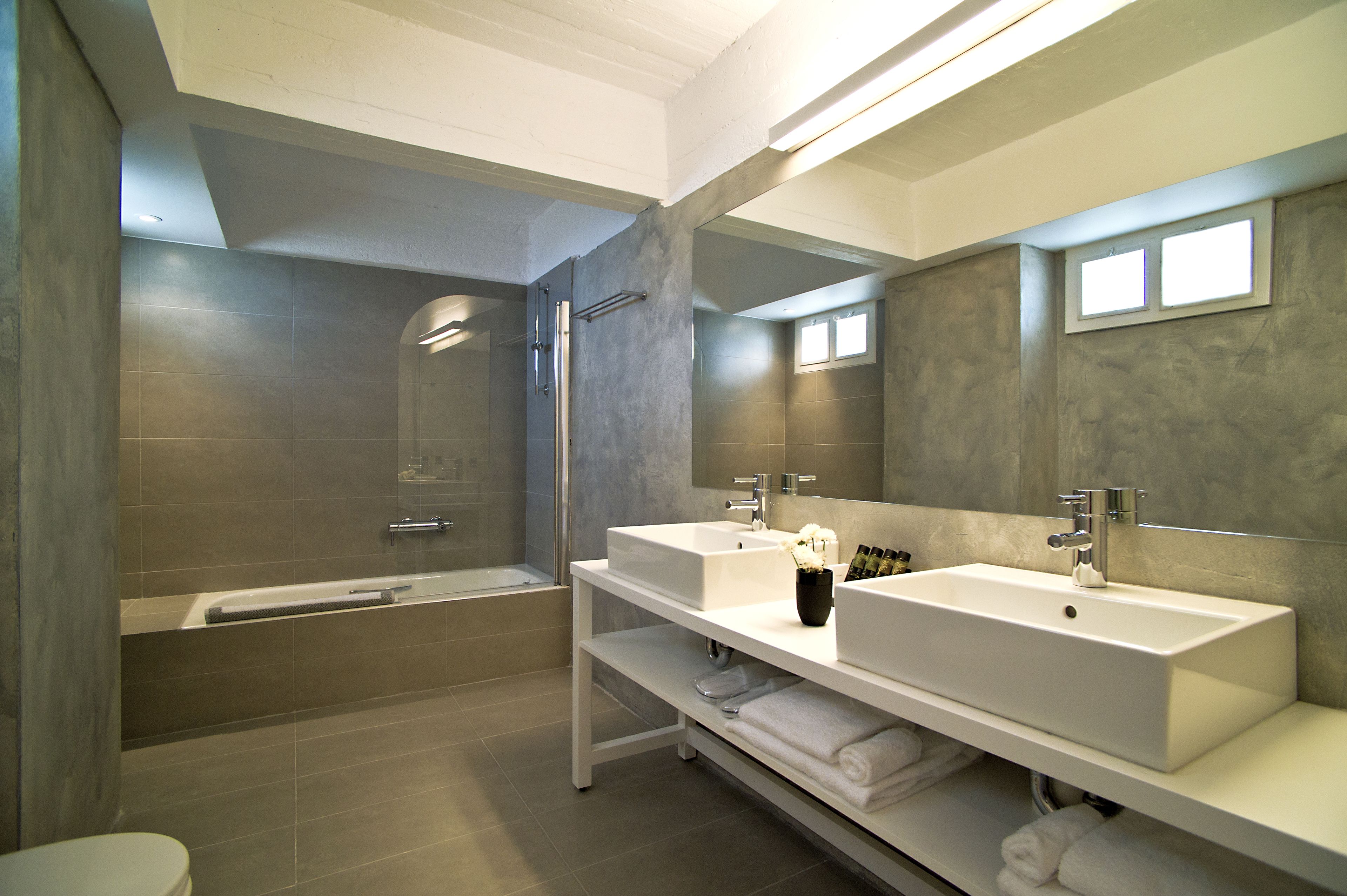 Een moderne badkamer met twee wasbakken, een douche en een toilet.